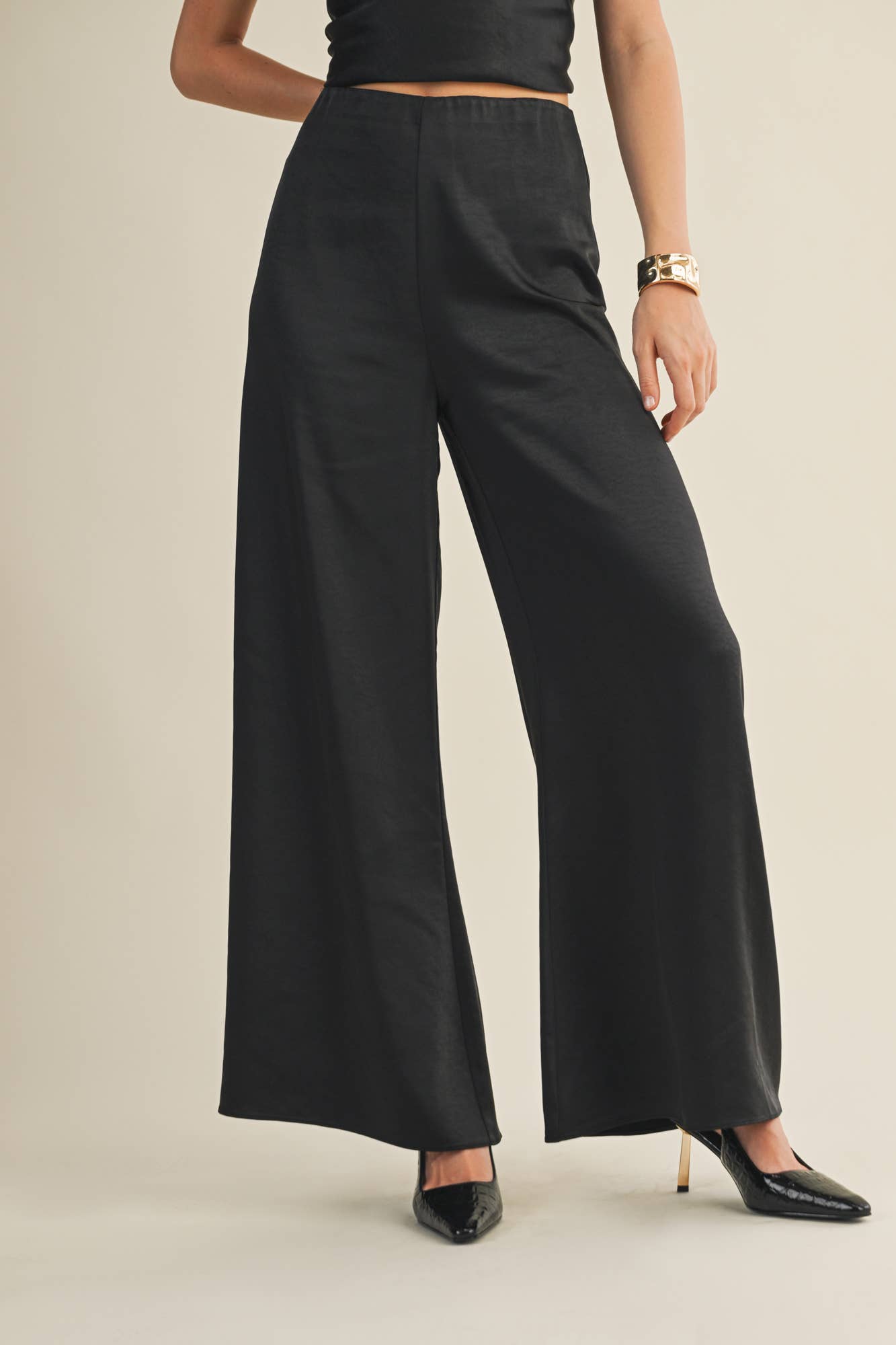 Elegant satin trousers in black featuring wide-leg silhouette and zipper closure.